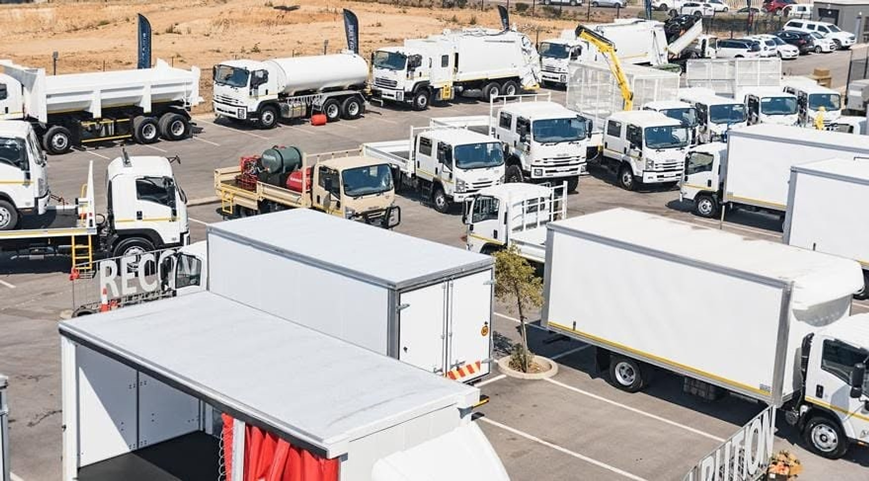 Mixed fleet of white commercial trucks at a transport yard